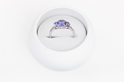 Lot 23 - A THREE STONE TANZANITE DRESS RING, mounted in...