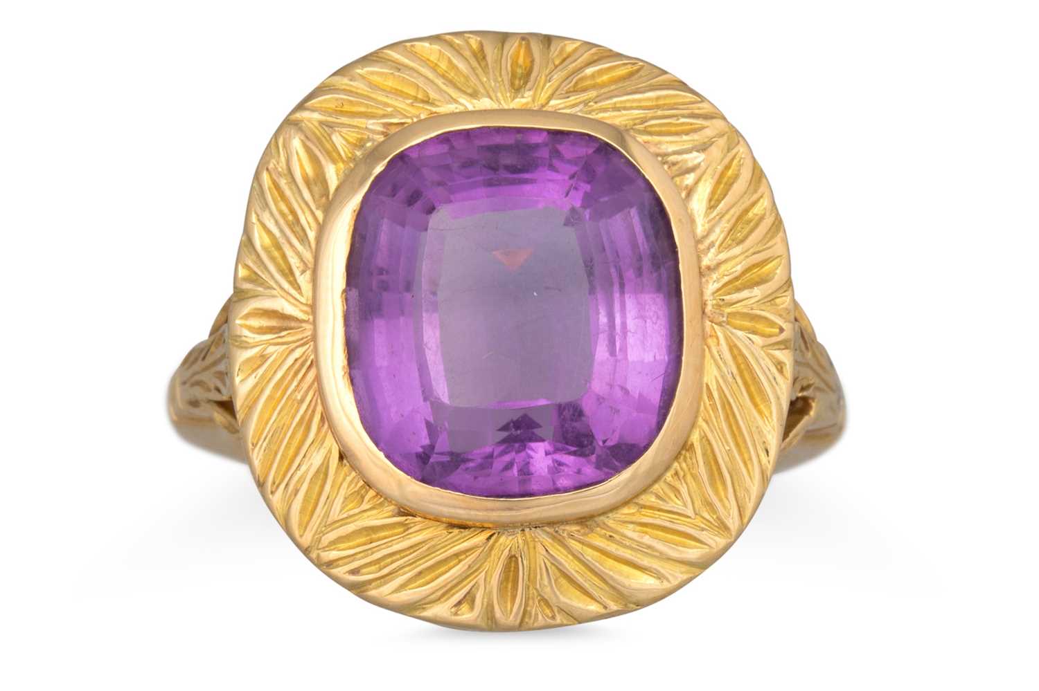 Lot 77 - AN AMETHYST RING, carved decoration to gold...