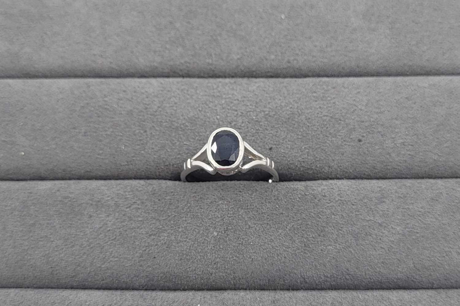 Lot 32 - A SAPPHIRE SET RING, the bezel set oval...
