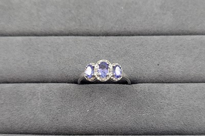 Lot 66 - A TANZANITE AND DIAMOND CLUSTER RING, the oval...