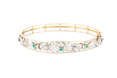 Lot 385 - AN EMERALD AND DIAMOND BANGLE, of floral form,...