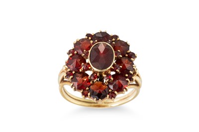 Lot 56 - A GARNET SET CLUSTER RING, the central oval...