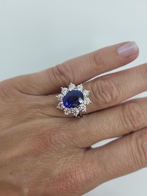 Lot 42 - A SAPPHIRE AND DIAMOND CLUSTER RING, the oval...