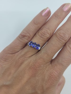 Lot 67 - A THREE STONE TANZANITE RING, the three oval...