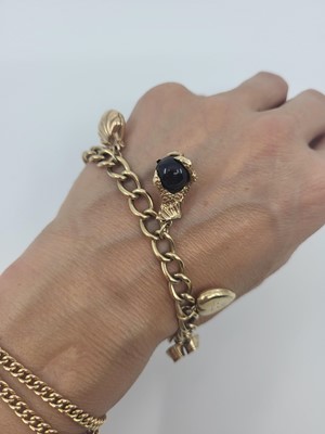 Lot 49 - A 9CT YELLOW GOLD CHARM BRACELET, set with...