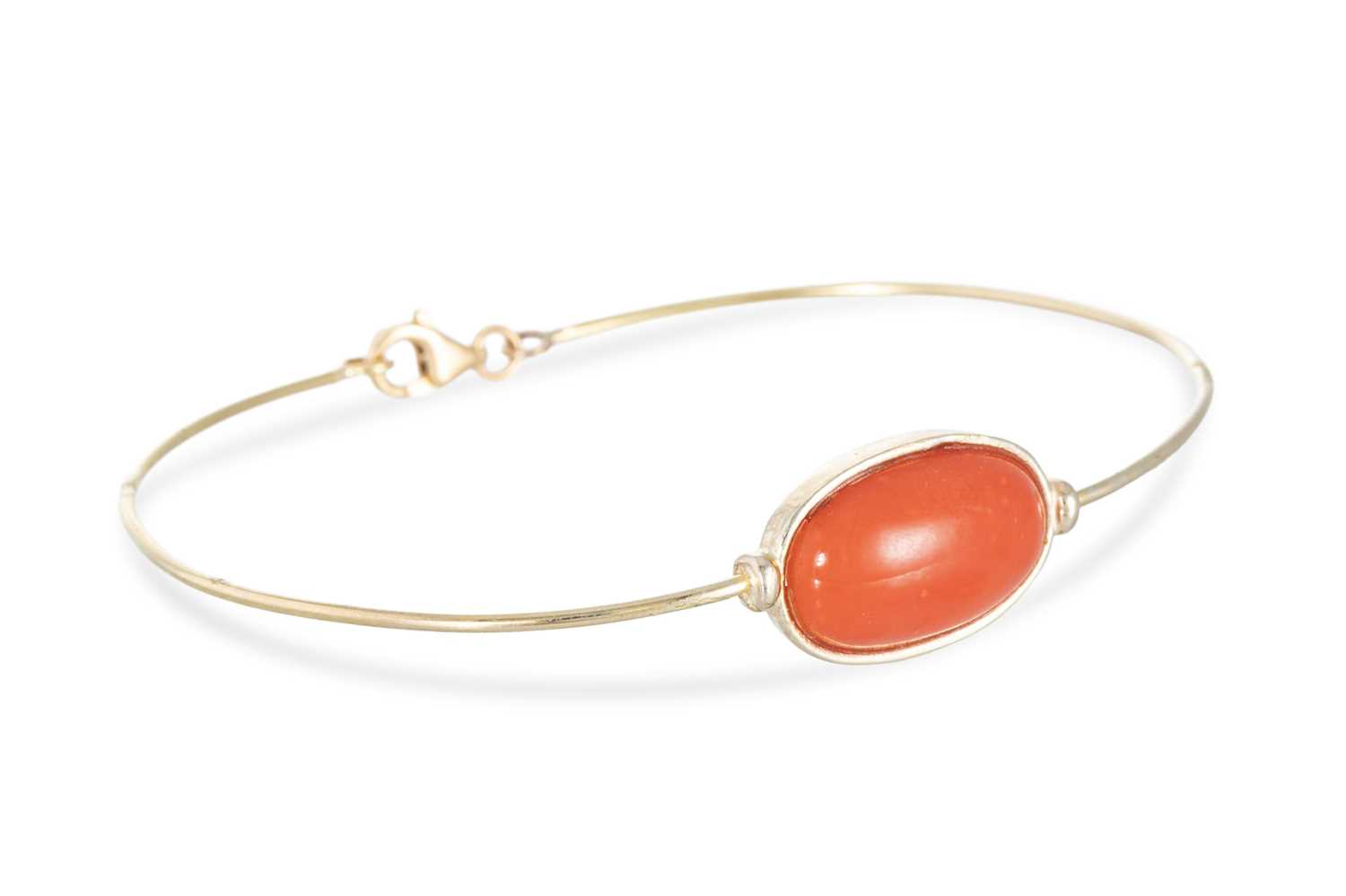 Lot 59 - A CORAL SET BANGLE, the bezel set cabochon...